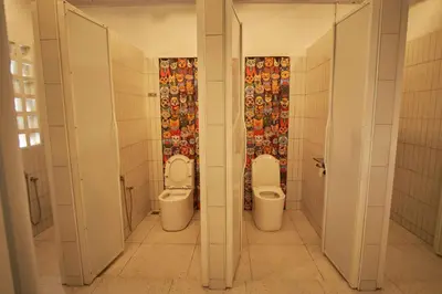 two toilets in a bathroom with two urinals at Some Place Else in George Town