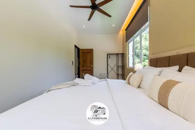 a bedroom with a large white bed with a ceiling fan at La Ferringhi Villa in Batu Ferringhi