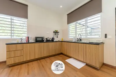 a kitchen with wooden cabinets and a counter top at La Ferringhi Villa in Batu Ferringhi