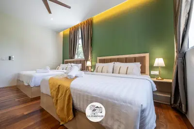 two beds in a bedroom with green walls and wooden floors at La Ferringhi Villa in Batu Ferringhi