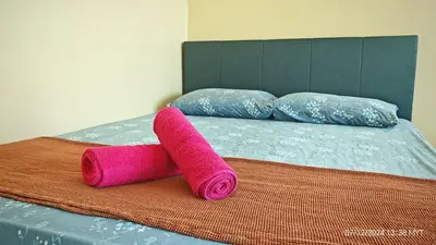 a pair of pink towels on a bed with pillows at Homestay Qasrina Semi D 4 Bilik in Kepala Batas