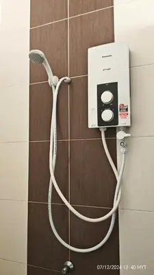 a shower with a white hose attached to a wall at Homestay Qasrina Semi D 4 Bilik in Kepala Batas