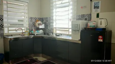 a kitchen with black cabinets and a sink and a window at Homestay Qasrina Semi D 4 Bilik in Kepala Batas