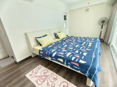 a bedroom with a bed with a blue comforter and a rug at Maritime Suite Penang - City & Sea view in George Town