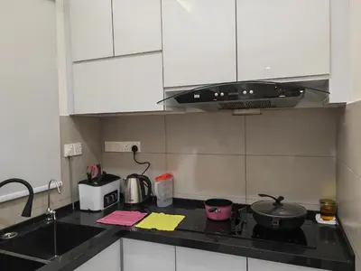 a kitchen with white cabinets and a black counter top at Meritus Premium Home Suite 8 Pax in Perai