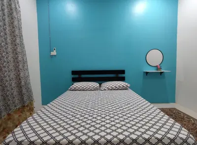 a bedroom with a bed with a blue wall at 32 Impian Homestay, Taiping in Taiping