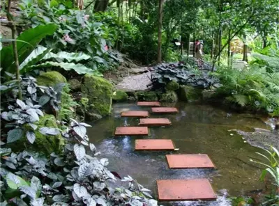 a path in a garden with red stones in the water at Bintara Guesthouse Sri Sayang Batu Ferringhi in Batu Ferringhi