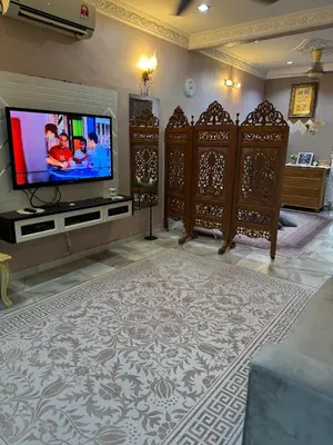 a living room with a flat screen tv and wooden furniture at NuLya Homestay in Kepala Batas