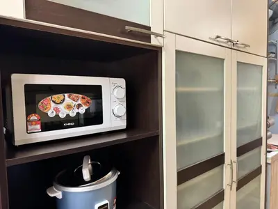 a microwave oven sitting on a shelf in a kitchen at NuLya Homestay in Kepala Batas