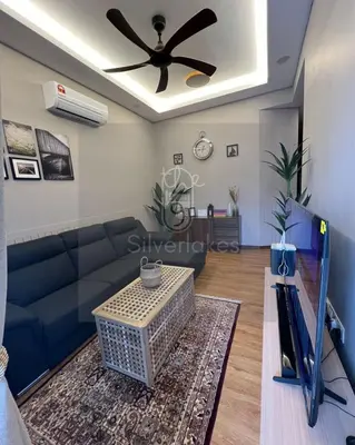 a living room with a blue couch and a ceiling fan at The9 Silverlakes Homestay in Batu Gajah