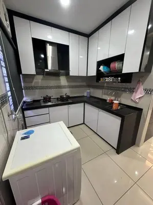 a kitchen with white cabinets and a black counter top at H&H Homestay Premium House in Kepala Batas