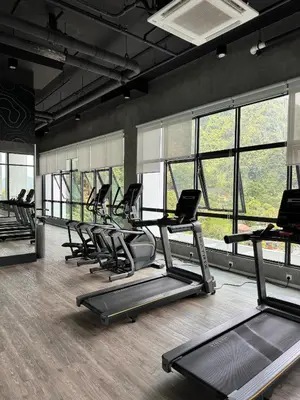 a gym with a row of treadmills and windows at Sunway Onsen Suite in Tambun
