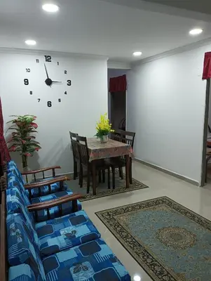 a dining room with a table and chairs and a clock at Yaakub homestay pangsapuri sutera jaya in Perai