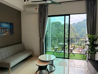 a living room with a couch and a table and a balcony at ONSTAY Sunway Onsen Suites in Ipoh