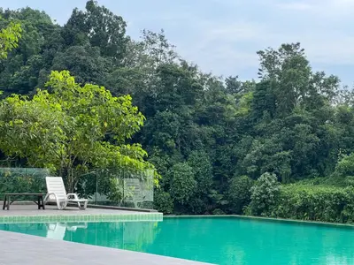 a chair sitting next to a swimming pool with trees at Crystal Creek 3BR Condo near Taiping Lake Garden & Zoo with WiFi Netflix in Taiping