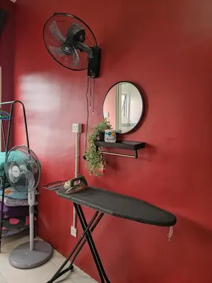 a red wall with a fan and a table with a mirror at DLAZ HOMESTAY in Tanah Rata