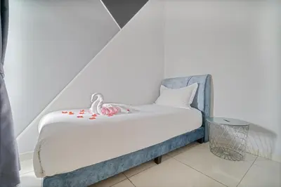 a small bed with white sheets and red decorations on it at The Horizon Ipoh Belle Vue by Grab A Stay in Ipoh