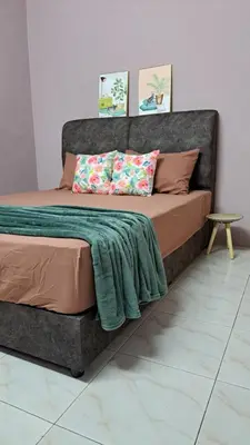 a large bed with a green blanket on top of it at Faza Homestay Meru Ipoh in Ipoh
