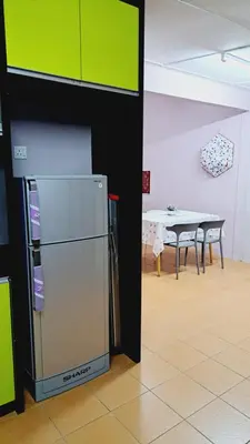 a kitchen with a refrigerator in a room with a table at Faza Homestay Meru Ipoh in Ipoh