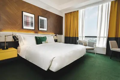 a hotel room with a large white bed and a chair at WEIL Hotel Ipoh in Ipoh