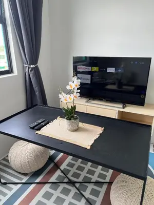 a black coffee table with a tv and flowers on it at Nixy Studio Seri Iskandar in Seri Iskandar