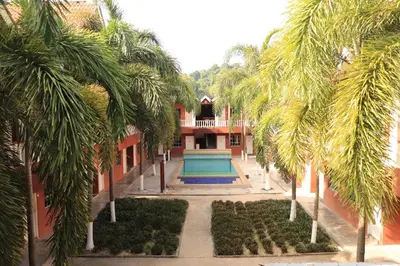 a building with a swimming pool and palm trees at Hornbillbay Beach Resort in Kampung Teluk Nipah
