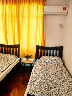a bedroom with two beds and a yellow curtain at Cozy & Comfy 3 rooms apartment near beach in Batu Ferringhi