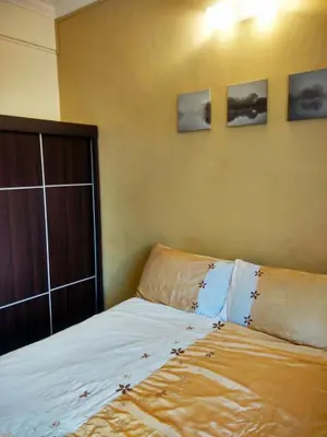 a bed in a room with three pictures on the wall at Cozy & Comfy 3 rooms apartment near beach in Batu Ferringhi