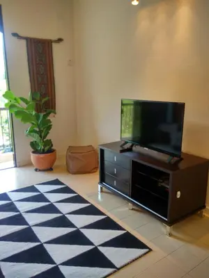 a living room with a flat screen tv on a cabinet at Cozy & Comfy 3 rooms apartment near beach in Batu Ferringhi