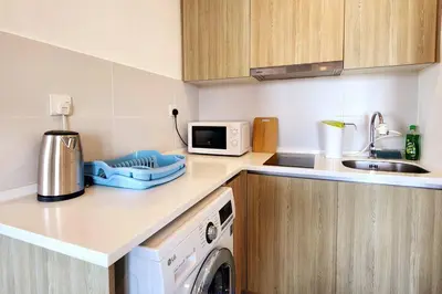 a kitchen with a washing machine and a microwave at Seaview Studio Tropicana 218 Macalister Georgetown in George Town