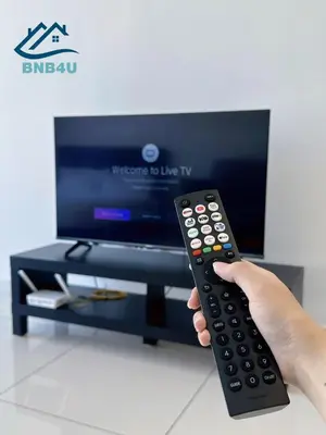 a person holding a remote control in front of a tv at Beacon 2BR Infinity Pool - By BNB4U in George Town