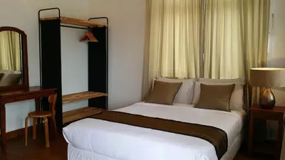 a bedroom with a large white bed with a mirror at Beach Front Bungalow Tanjung Bungah in George Town