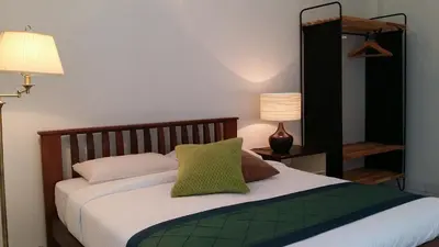 a bedroom with a bed with white sheets and green pillows at Beach Front Bungalow Tanjung Bungah in George Town
