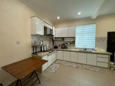 a kitchen with white cabinets and a wooden table at Homestay Bagan Serai in Bagan Serai