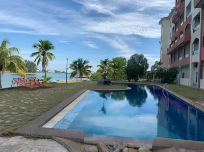 a swimming pool in front of a building with a body of water at A sweet home for your trip in Lumut