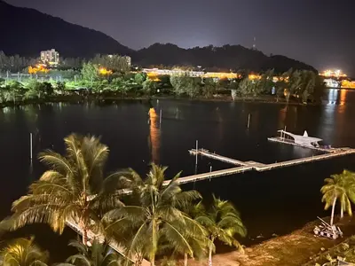a river with palm trees and a dock at night at A sweet home for your trip in Lumut