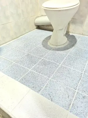 a bathroom with a toilet on a blue tile floor at Pine Lodge BY EVR Previously YSS indrawasih in Perai