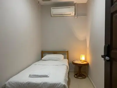a small bedroom with a bed and a night stand with a lamp at Aayu Muntri - 4 mins to Chulia St George Town in George Town