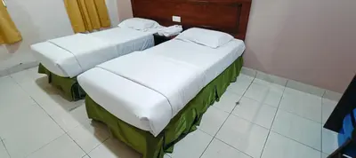 two beds in a room with white tile floors at Kampar Times Inn Hotel in Kampar