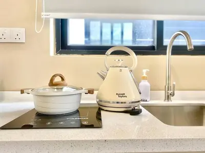 a tea kettle sitting on a counter next to a sink at Urban Suites #Soft creamy #Infinity Pool #local neighbourhood #4pax #2BR 2bath #2Queen #Quality well maintained #Private host in Jelutong