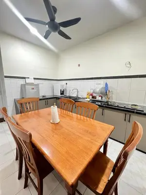 a wooden table in a kitchen with a ceiling fan at De Raisha Homestay in Butterworth