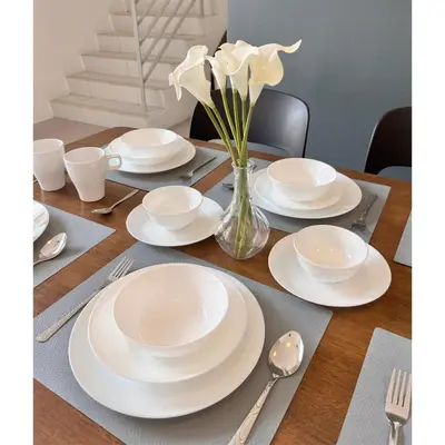 a table with white plates and a vase of flowers at Aloft Cameron Highlands C in Brinchang