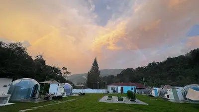 a rainbow in the sky over a group of tents at The Starry Dome Couple Room in Cameron Highlands
