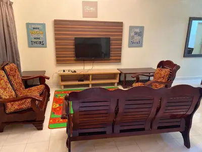 a living room with two chairs and a flat screen tv at Highlands Double Story House in Tanah Rata