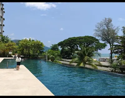 a man standing next to a swimming pool at By The Sea Beach Front and Seaview Apartment 2 in Batu Ferringhi