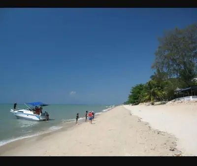 a group of people standing on a beach next to a boat at By The Sea Beach Front and Seaview Apartment 2 in Batu Ferringhi