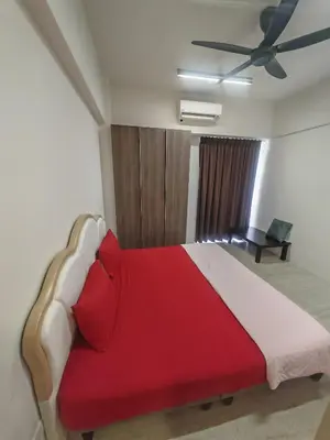 a bedroom with a red bed with a ceiling fan at By The Sea Beach Front and Seaview Apartment 2 in Batu Ferringhi