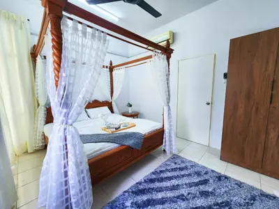 a bedroom with a canopy bed with a blue rug at Ipoh Apartment Casa Klebang 31200 Chemor Ipoh in Chemor