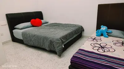 a bedroom with two beds and a blue teddy bear at Sterling Homestay in Tanjung Bungah