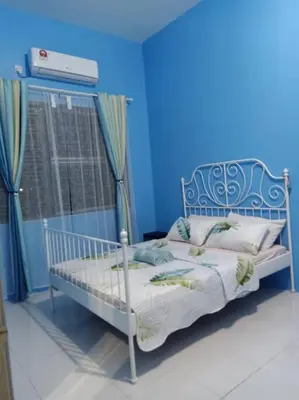 a blue bedroom with a bed with a blue wall at Bota TheDaun Homestay Taman Indera in Kampung Bota Kiri